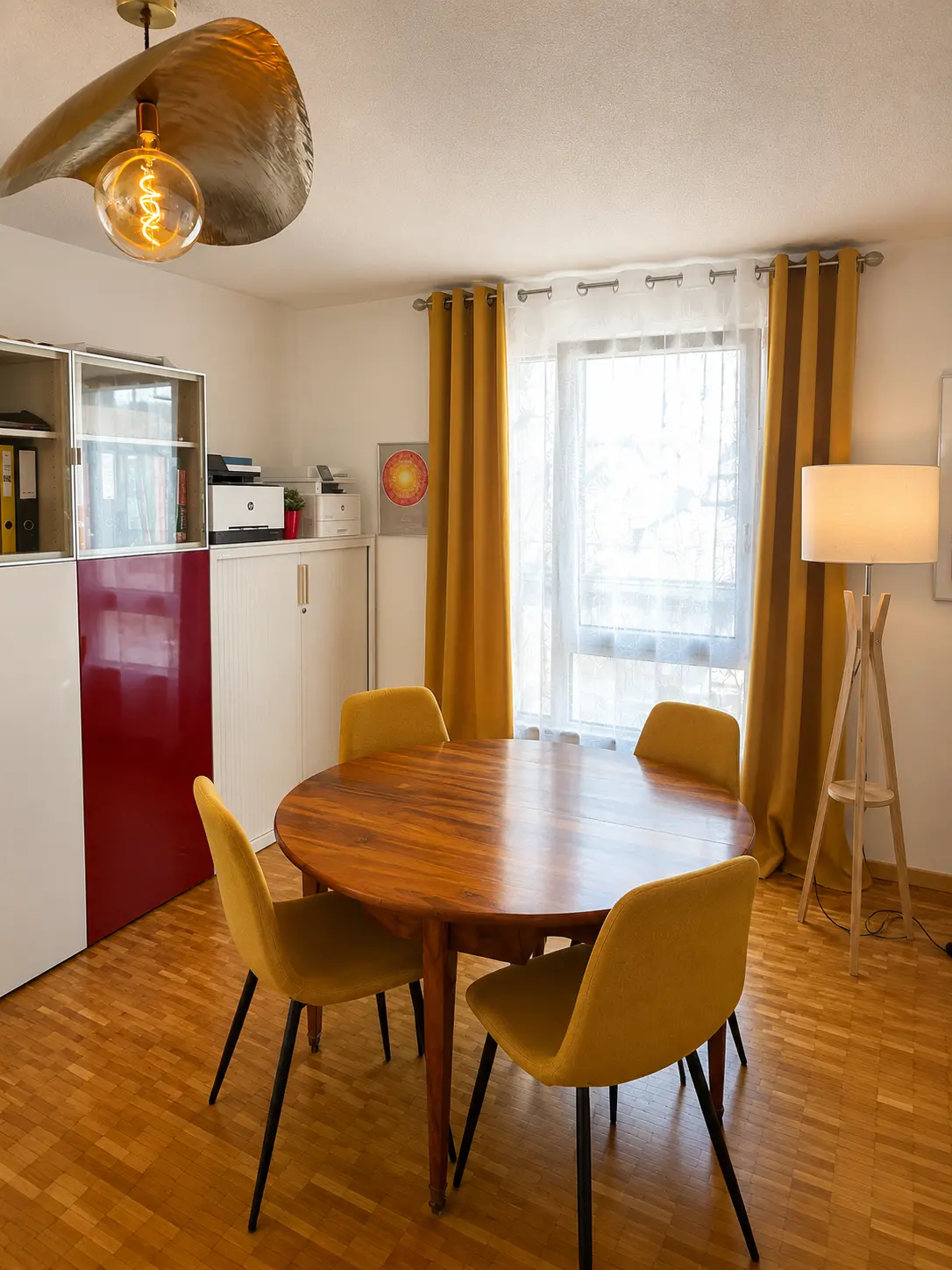Cabinet d’Épalinges : table ronde en bois, chaises jaunes et lumière naturelle