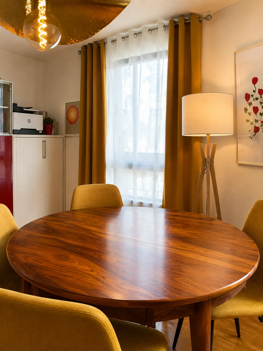 Table ronde du cabinet d’Épalinges éclairée par une lampe et de grands rideaux dorés